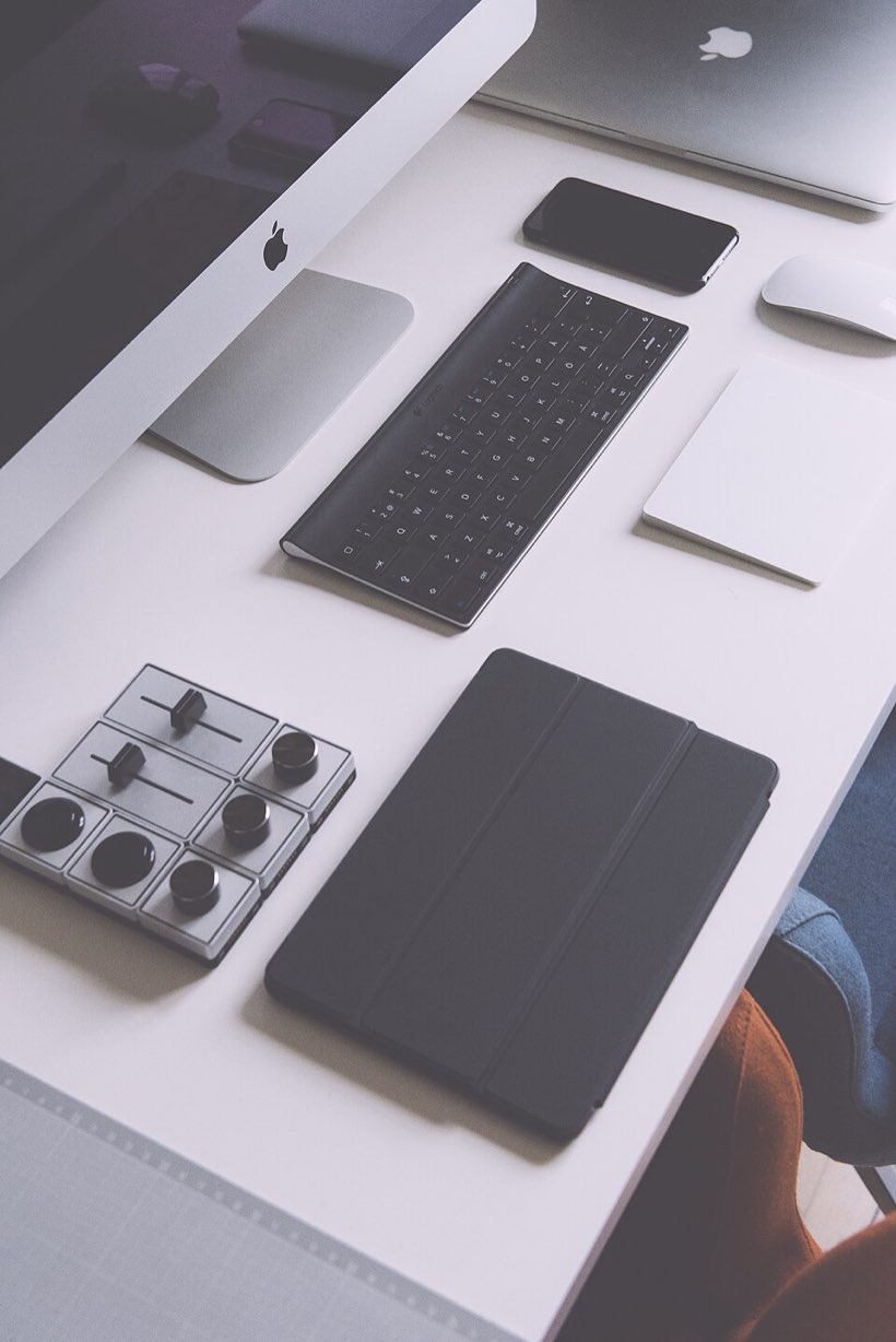 A phone, notebook and small gadgets laid out on a working desk